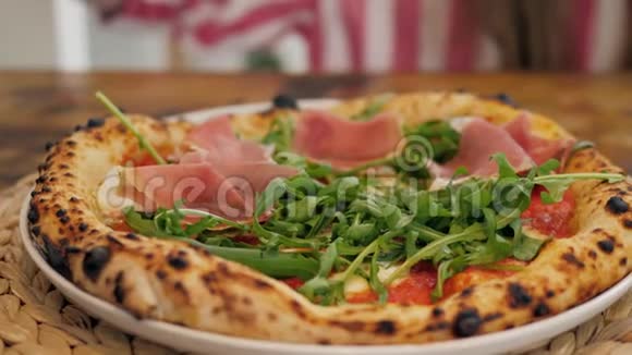 披萨店的厨师准备一个披萨并用意大利火腿装饰它绿色草本植物接近视频的预览图