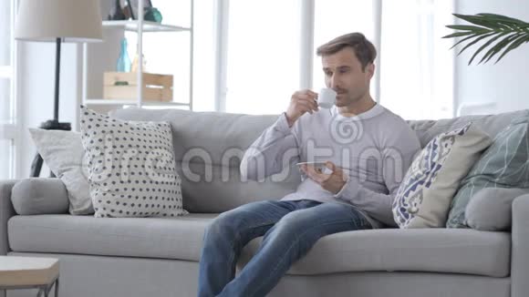 成人在沙发上喝咖啡和放松视频的预览图