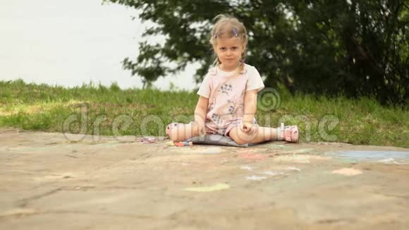 一个漂亮的小女孩在海滨长廊旁边的小径上画粉笔视频的预览图