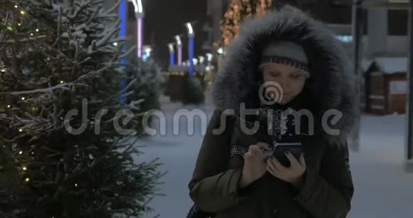 女人用手机在街上散步装饰圣诞节视频的预览图