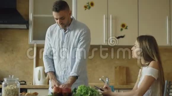 一对漂亮的夫妇一大早就在厨房里聊天英俊的男人一边做饭一边喂老婆视频的预览图