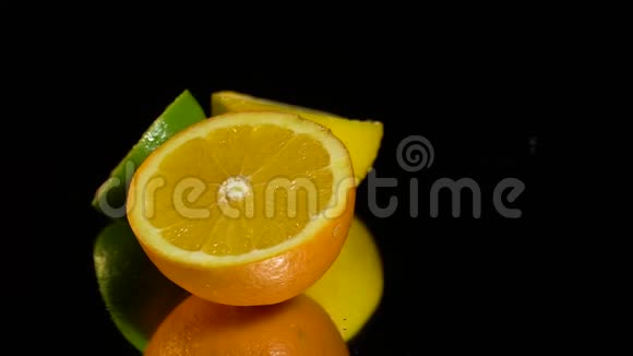 黑色背景下的柠檬橘子和石灰半块视频的预览图
