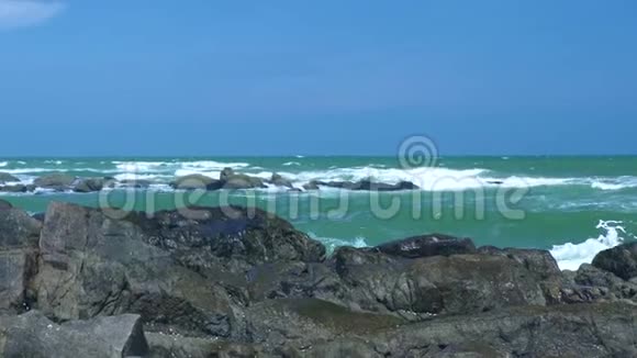 波涛汹涌的大海和海浪溅落在岩石海滩上的蓝天景观海浪在海洋中的石滩上肆虐视频的预览图