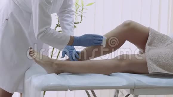 美容师在上面涂上一条材料热蜡去除腿上的毛发视频的预览图