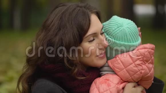 秋天公园里有个孩子的美丽年轻女人的肖像小女孩在哭年轻母亲安慰女儿视频的预览图