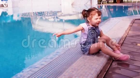 蓝色游泳池旁的小女孩一个小孩子在游泳池旁边玩一个漂亮的小女孩正坐在一个视频的预览图