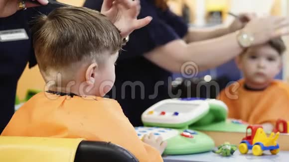儿童发型理发师在理发店和小男孩一起工作视频的预览图