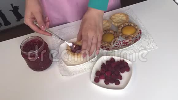 一个女人把一勺树莓果酱作为馅放入烤好的蛋糕预制件中视频的预览图
