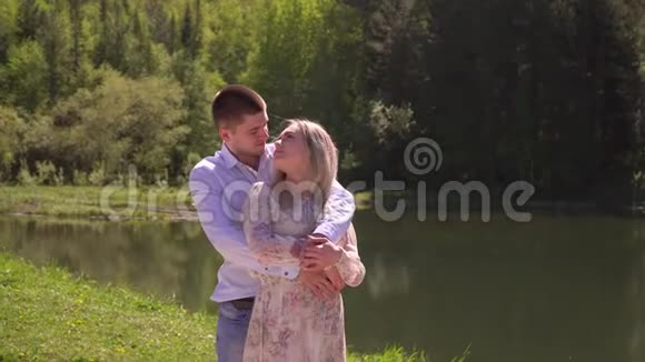 可爱的夫妇拥抱在湖畔拥抱漂亮的家伙和女孩站在一个拥抱上视频的预览图