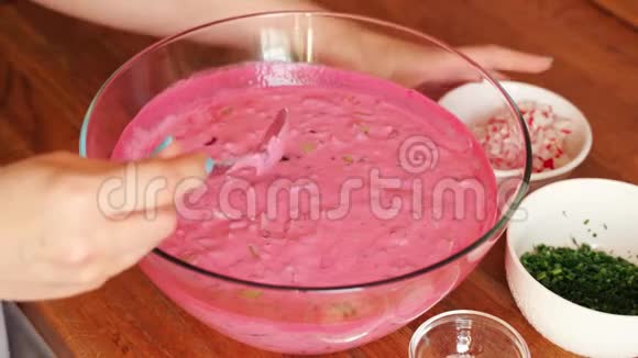 女人在木桌上的玻璃碗里准备冷甜菜根汤视频的预览图