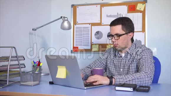 办公室工作人员在笔记本电脑上打印文本时看着监视器喝茶视频的预览图