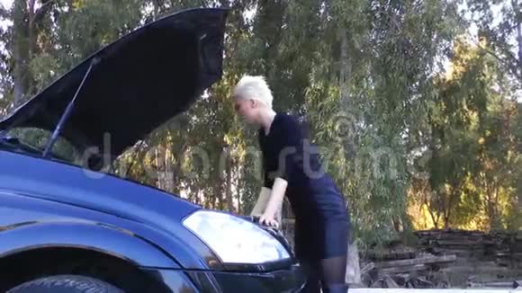 年轻的金发女郎正在修理汽车发动机视频的预览图