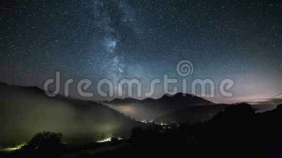 银河系的恒星在雾谷之上的山脉上移动星空夜晚时间流逝视频的预览图