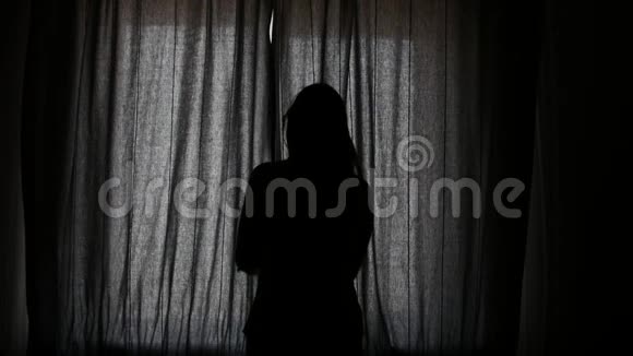 年轻女子揭开窗帘望着窗外视频的预览图