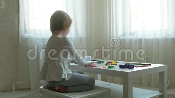一个小女孩玩橡皮泥用手把它卷起来桌面上有数字和彩色铅笔视频的预览图