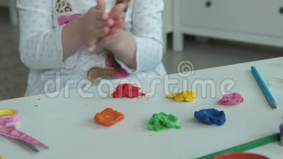 快乐的小女孩玩着彩色橡皮泥雕刻着一个图形桌面上是图形和彩色铅笔视频的预览图