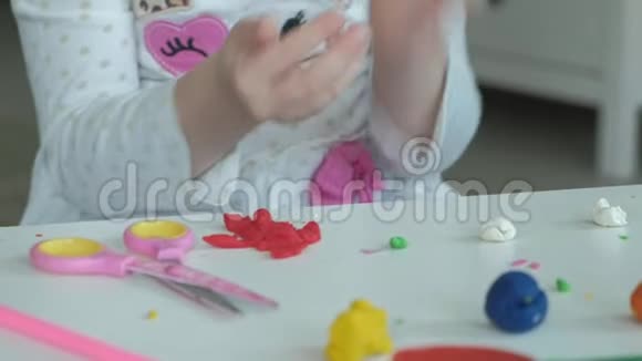 一个小女孩玩橡皮泥用手滚球桌面上有数字和彩色铅笔视频的预览图