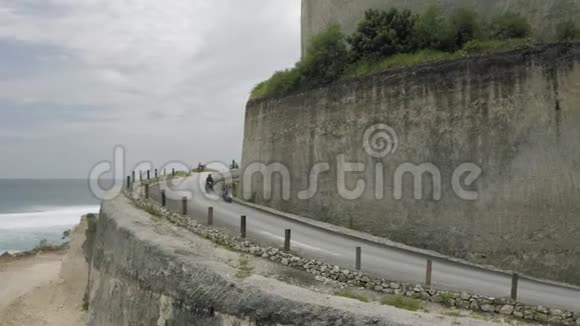 在UluwatuBali海滩和岩石的公路上骑自行车视频的预览图