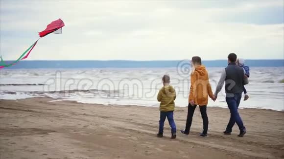 幸福的一家人沿着海岸散步男人女人小男孩和女孩视频的预览图