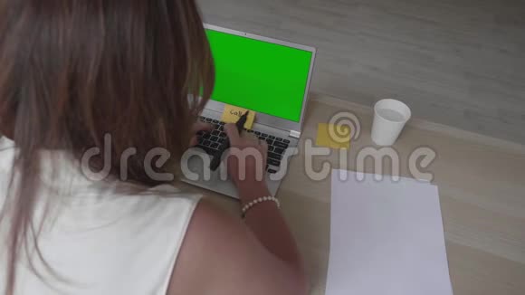 年轻女子坐在桌子上手提电脑上有绿色的屏幕和各种准备白天的计划视频的预览图