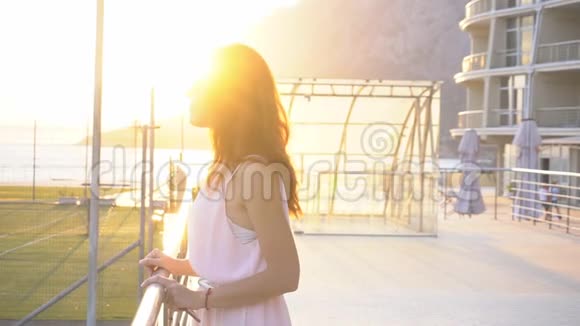 日落时分度假村的女孩站在海边视频的预览图