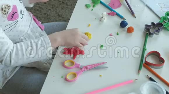 快乐的小女孩玩橡皮泥雕刻一个图形桌面上是图形和彩色铅笔视频的预览图