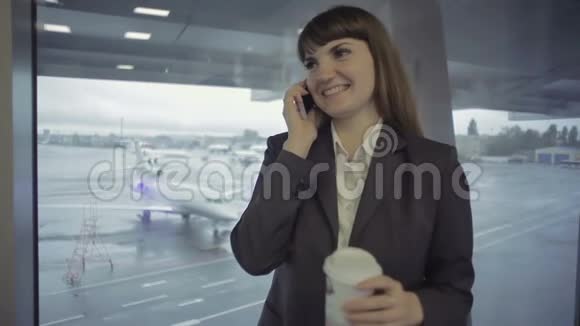 女商人在靠近窗户的机场大厅打电话视频的预览图