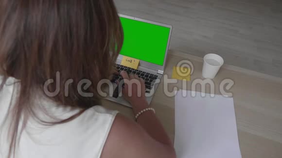 年轻女子坐在桌子上手提电脑上有绿色的屏幕和各种准备白天的计划视频的预览图