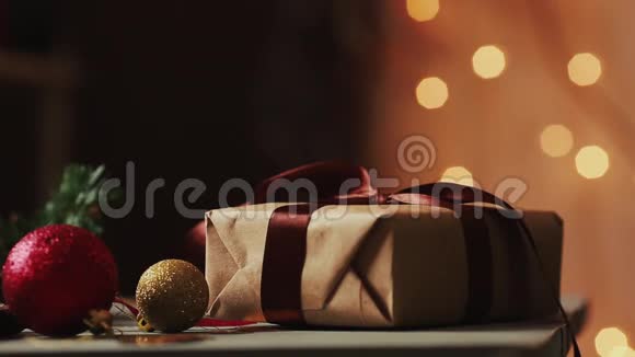 在圣诞灯光的背景下女人手把丝带绑在牛皮纸上背景视频的预览图
