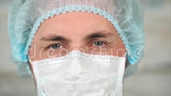 一位年轻的男医生戴着防护破布面具头戴帽子的肖像视频的预览图