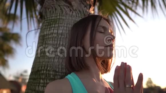 一个年轻漂亮的女孩在棕榈树上做瑜伽慢速运动4k视频的预览图