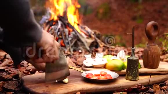 森林营火背景下用大斧头刀在木板上手工切蒜菜视频的预览图