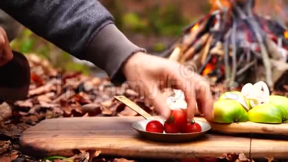 男人用手砍小樱桃番茄蔬菜用大厨斧刀砍在森林营地的木板上视频的预览图