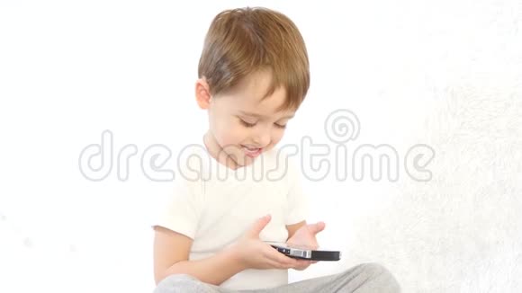 快乐的孩子在白色背景上玩智能手机微笑着特写镜头视频的预览图