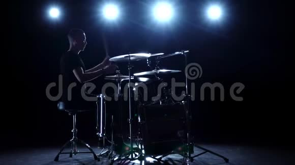鼓手在鼓上大力演奏旋律黑色背景背光剪影慢动作视频的预览图