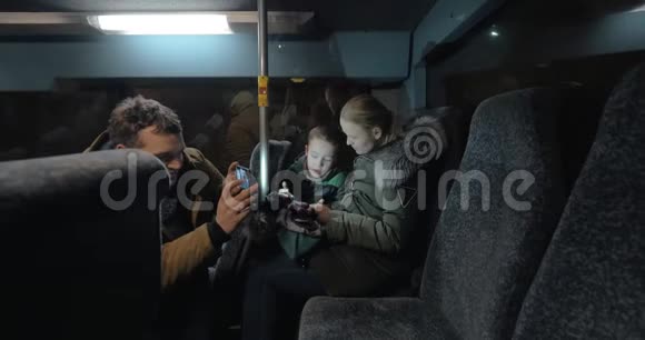 妈妈爸爸和儿子晚上乘公共汽车用手机视频的预览图