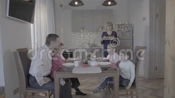 可爱快乐的四个孩子一家人在厨房餐桌上庆祝除夕父亲儿子女儿笑着母亲在服侍视频的预览图