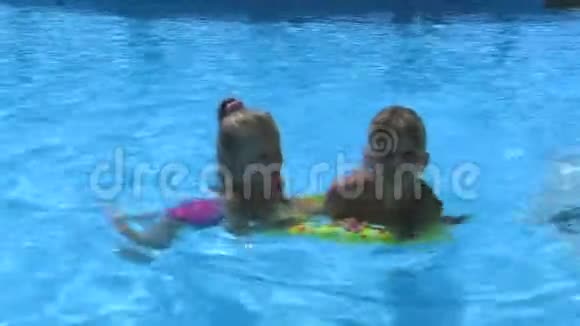 戴着太阳镜漂浮在充气环上的孩子正在游泳池里游泳视频的预览图