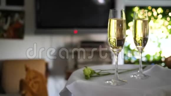 透明酒杯与结婚戒指在酒精饮料白色托盘与鲜花特写视频的预览图