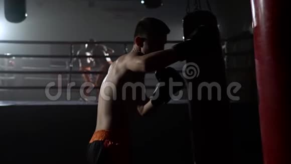 戴手套的家伙打梨花在戒指的背景上有一群拳击手慢动作视频的预览图