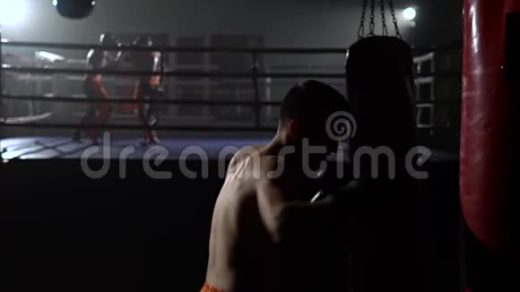 戴手套的男人打梨花在戒指的背景上有一群拳击手慢动作视频的预览图