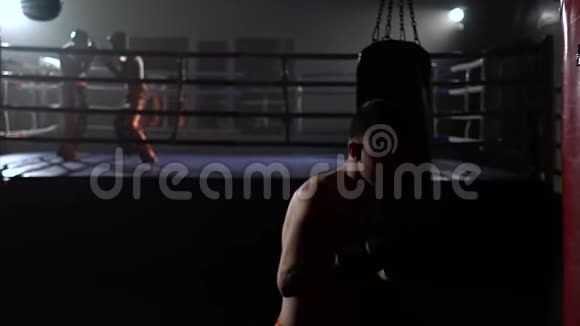 戴手套的家伙打梨花在戒指的背景上有一群拳击手慢动作视频的预览图