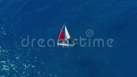 空中观景在开阔的海洋里航行着红帆的游艇视频的预览图