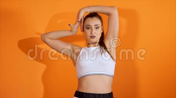 女性rnb舞者在橙色墙上的工作室里跳着时尚舞视频的预览图