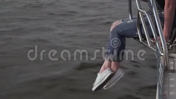 那个女孩坐在白色的游艇上从游艇的边缘垂下双腿年轻人喜欢飞行的天气在那儿视频的预览图