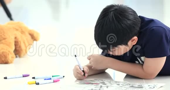 亚洲男孩躺在地板上用彩笔画画视频的预览图