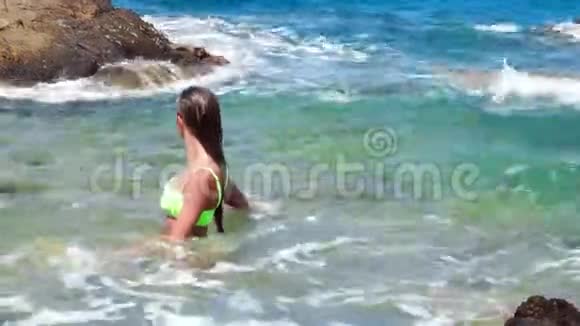 年轻女孩在荒凉的岩石海滩游泳视频的预览图