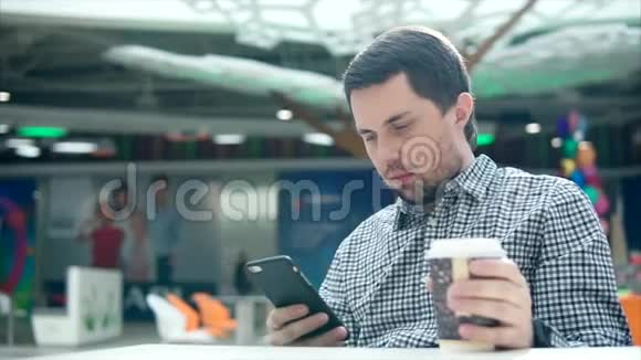 一个年轻人拿着电话和咖啡在另一只手里等他的女朋友视频的预览图