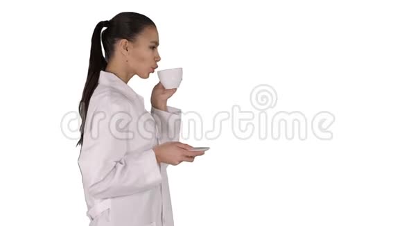年轻护士在白色背景下散步时放松地喝咖啡或茶视频的预览图