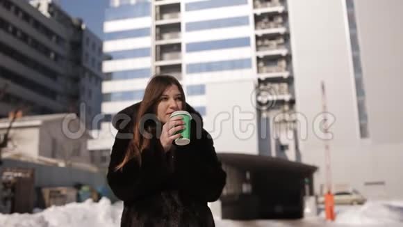 城市里的女孩冬天喝着绿杯子里的咖啡视频的预览图